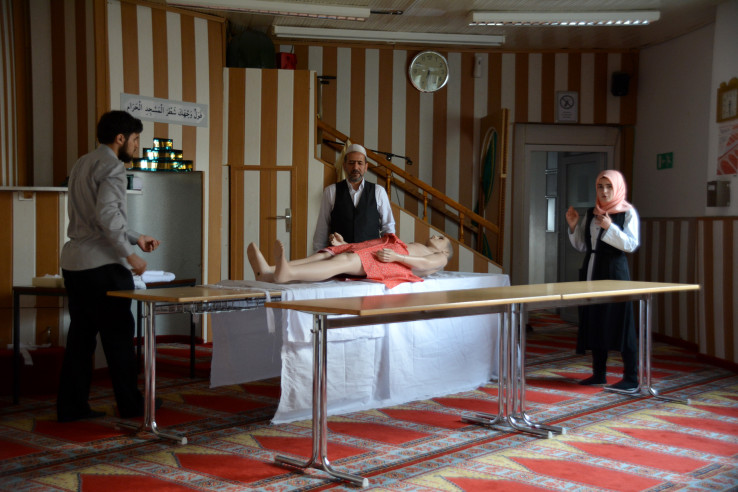 Drei Personen demonstrieren an einer Puppe die muslimische Leichenwaschung. Foto: Vera Lisakowski
