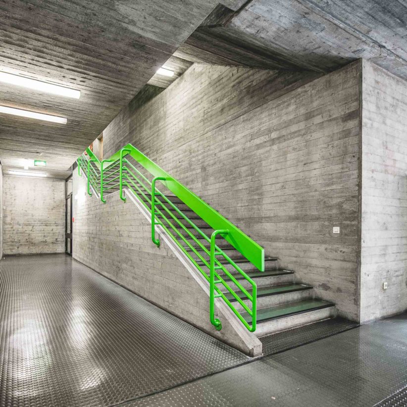 Leuchtend grünes Treppengeländer im Beton-Treppenhaus der Hochschule für Musik und Tanz Köln. Foto: Gregor Zoyzoyla